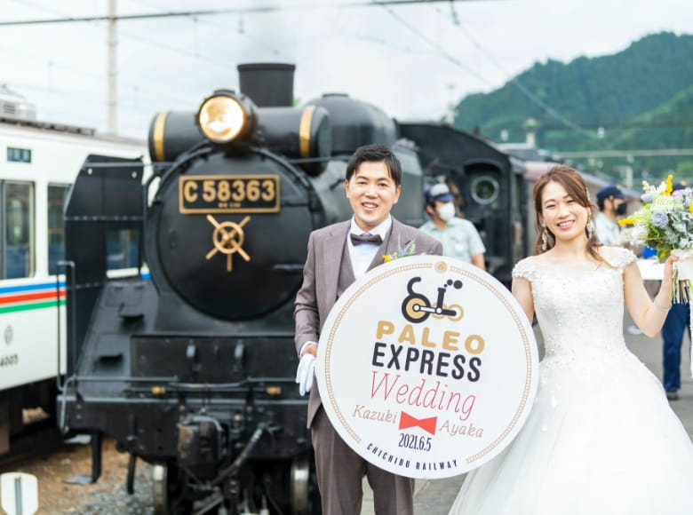 お名前入りSLヘッドマークを持つ新郎新婦の写真