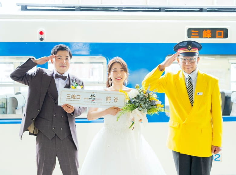 お名前入りのサボ掲出を持つ新郎新婦の写真