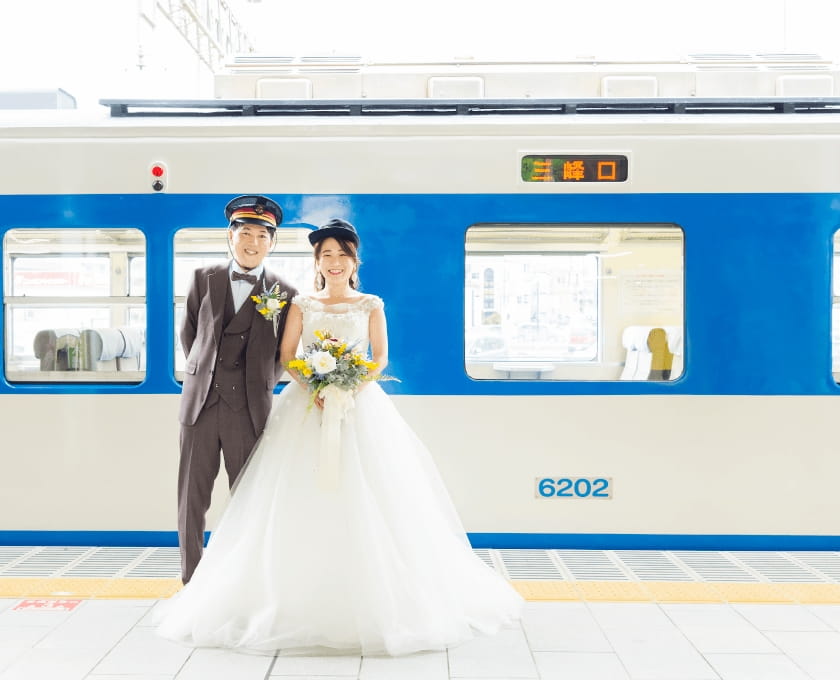 新郎新婦が駅のホームで笑っている写真