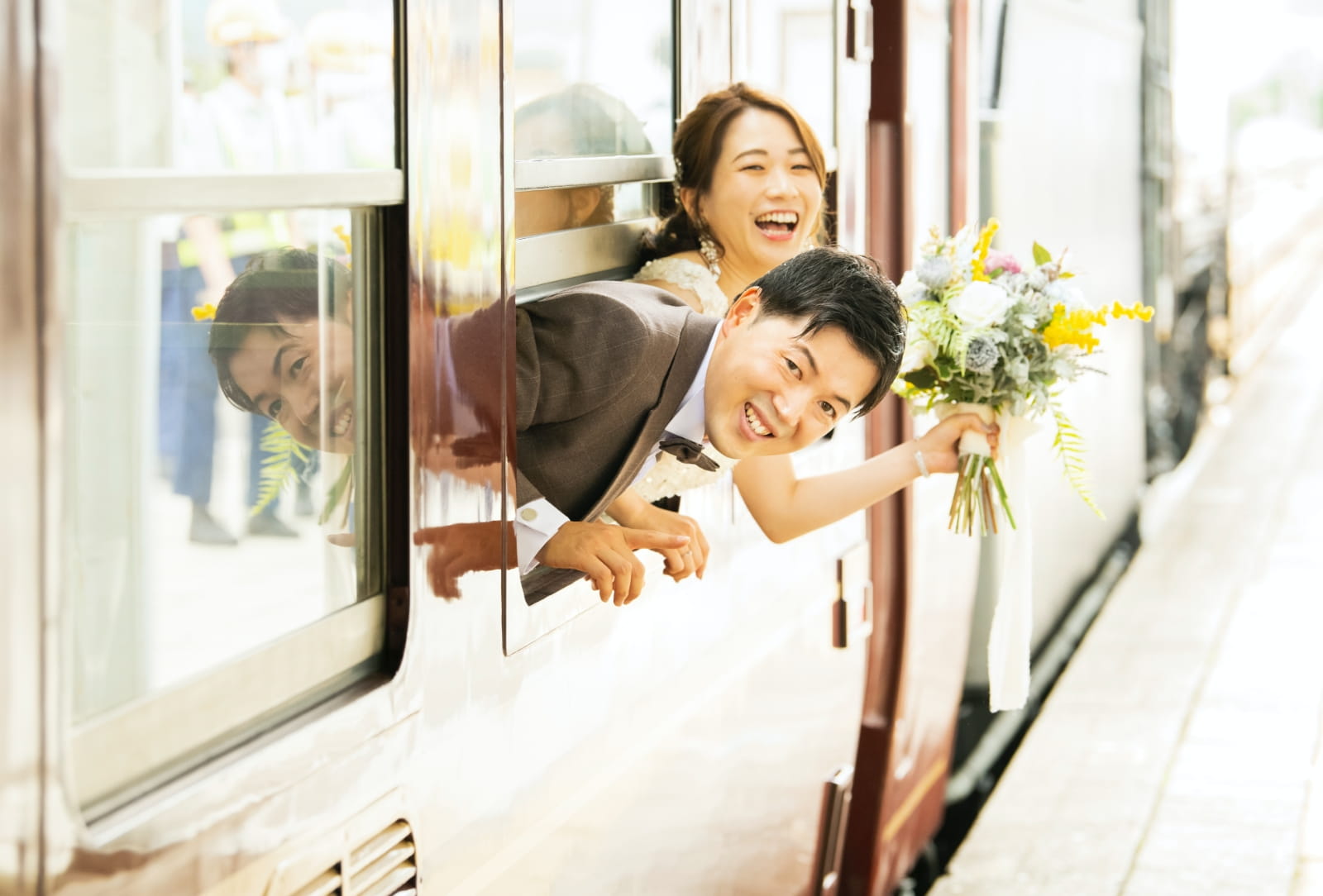 新郎新婦が笑顔で車窓から顔を出している写真